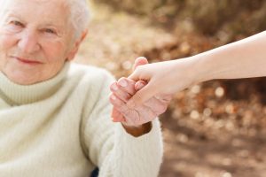 Elderly woman holding hands with a carer